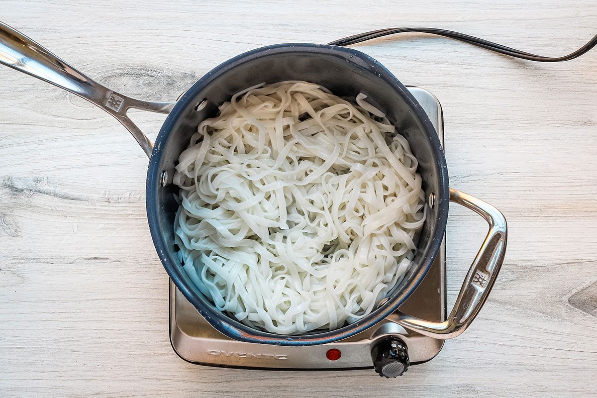 Peanut chicken stir-fry preparation: rice noodles cooked in the pan.