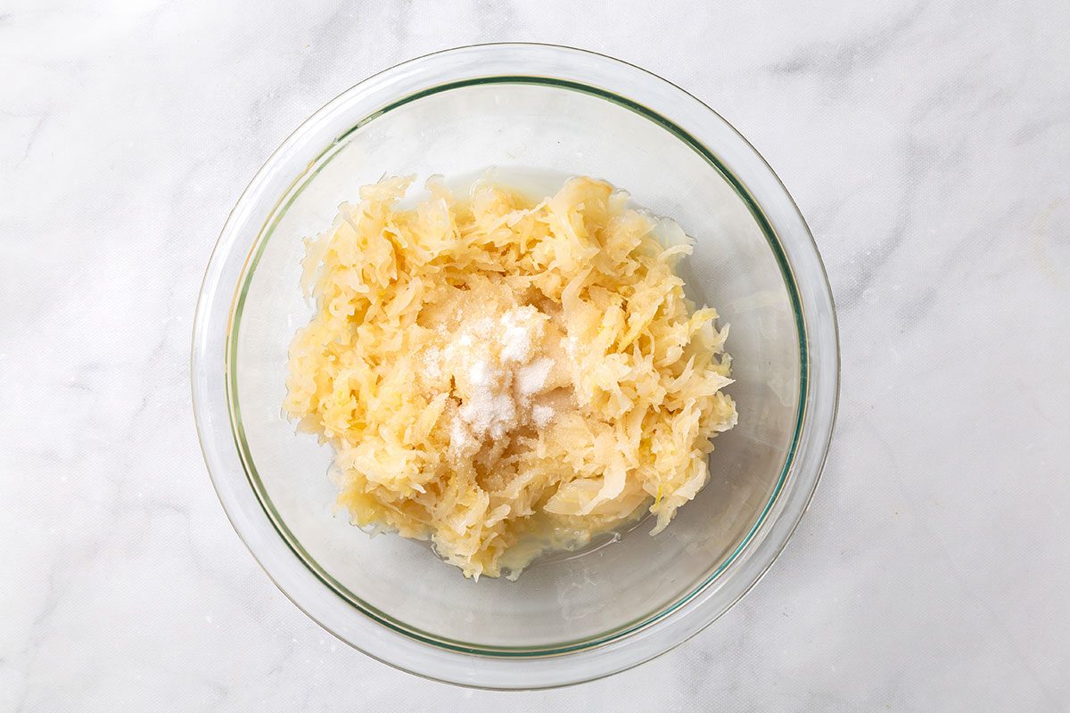 Sauerkraut mixed with sugar in a mixing bowl for step three of Pork Roast and Sauerkraut recipe for Taste of Home