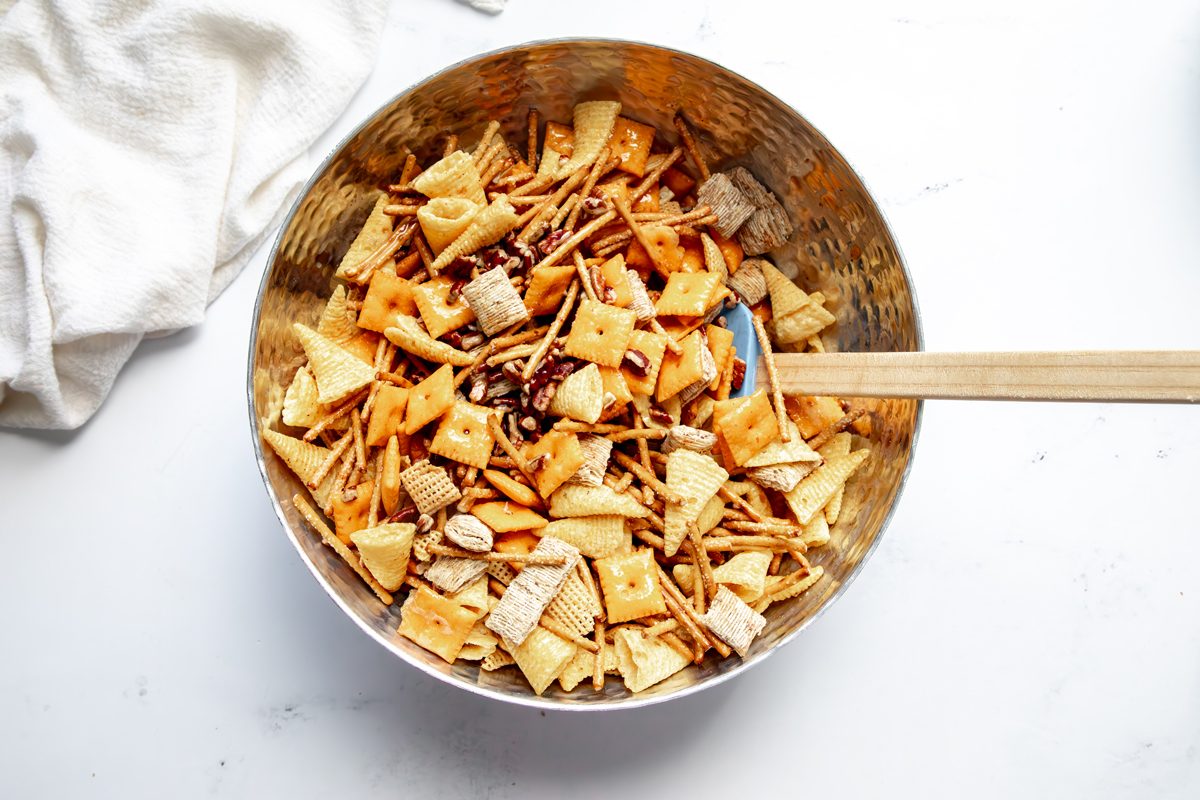 Overhead shot for Taste of Home Reindeer Chow, butter mixture being mixed into reindeer chow.