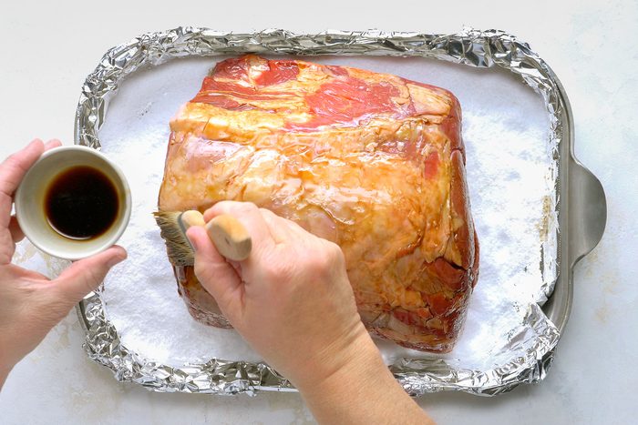 Brushing rib roast with Worcestershire sauce.