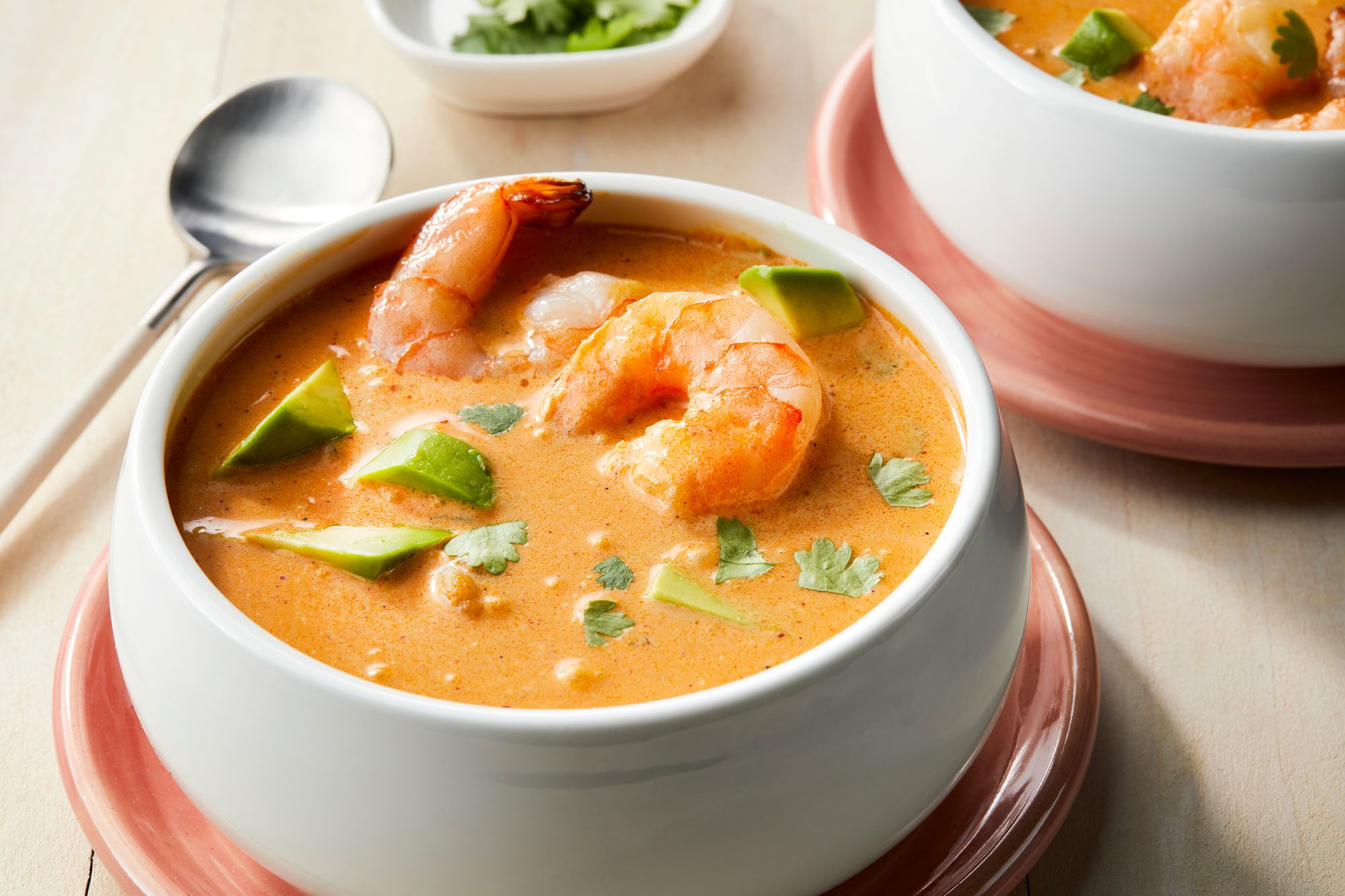 Shrimp Bisque served in two bowls garnished with cilantro, avocado and additional shrimp