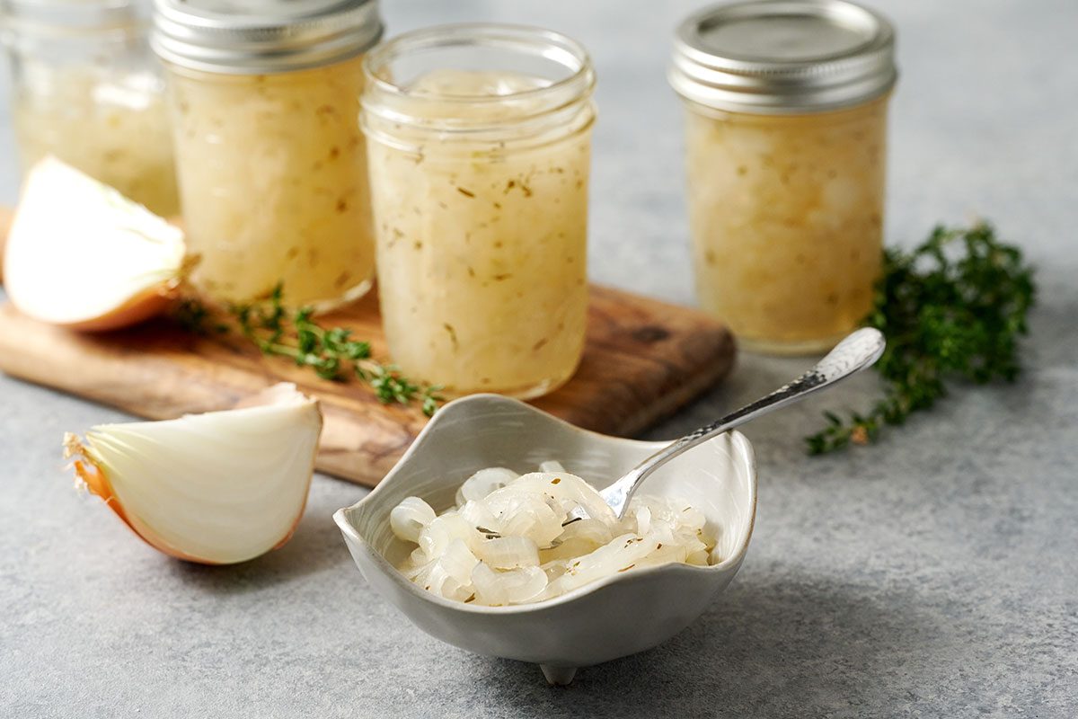Close-up horizontal shot of the Taste of Home Pickled Sweet Onions, highlighting the vibrant onions plated next the jars.