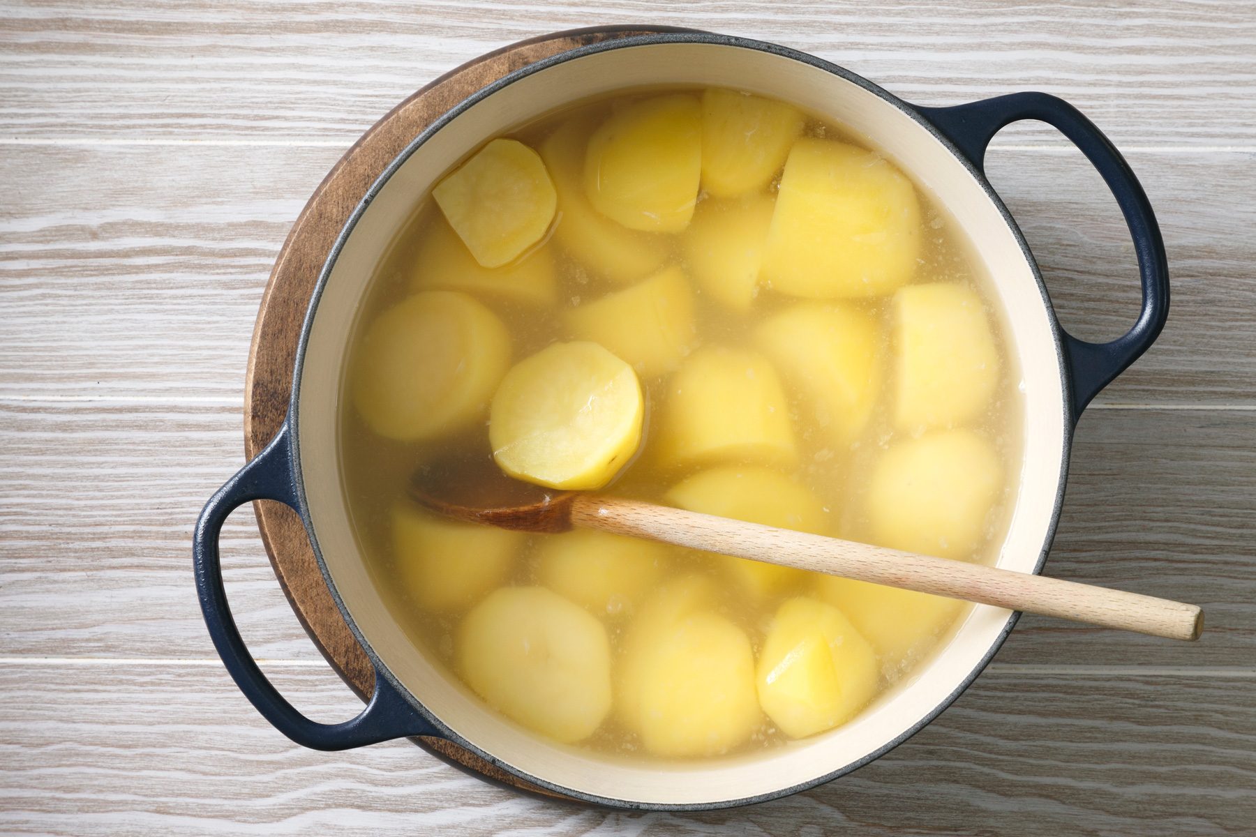 Overhead shot place potatoes in a stock pot; add water to cover; season water with 1 teaspoon salt; bring to a boil; reduce heat; cook; uncovered; until tender; 15-20 minutes; spoon; wooden surface;