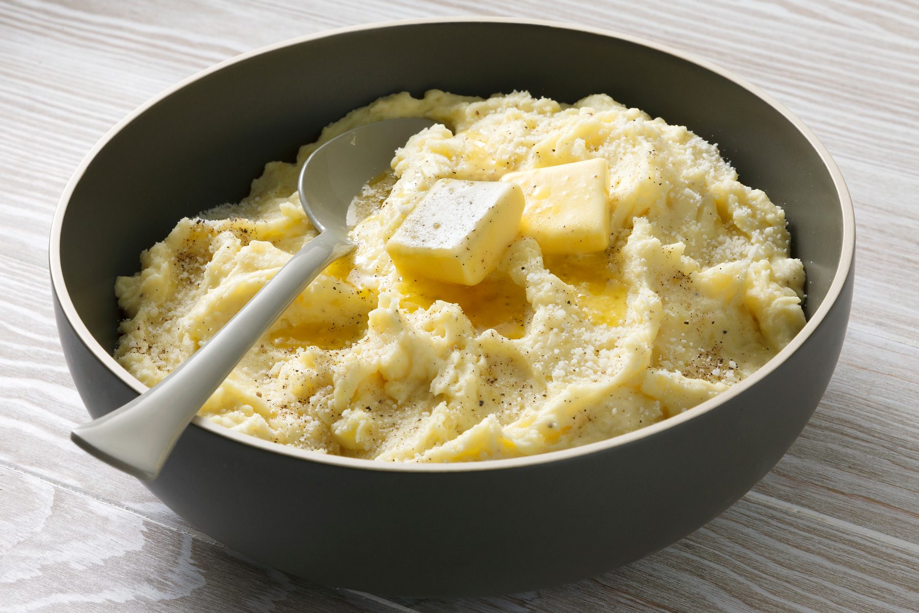 Table view shot of Truffle Mashed Potatoes; stir in remaining 1 teaspoon salt and pepper; sprinkle with truffle salt and additional Parmesan and pepper before serving; spoon; wooden surface;