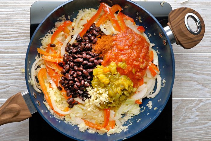 A variety of vegetables and beans cooking in a skillet.