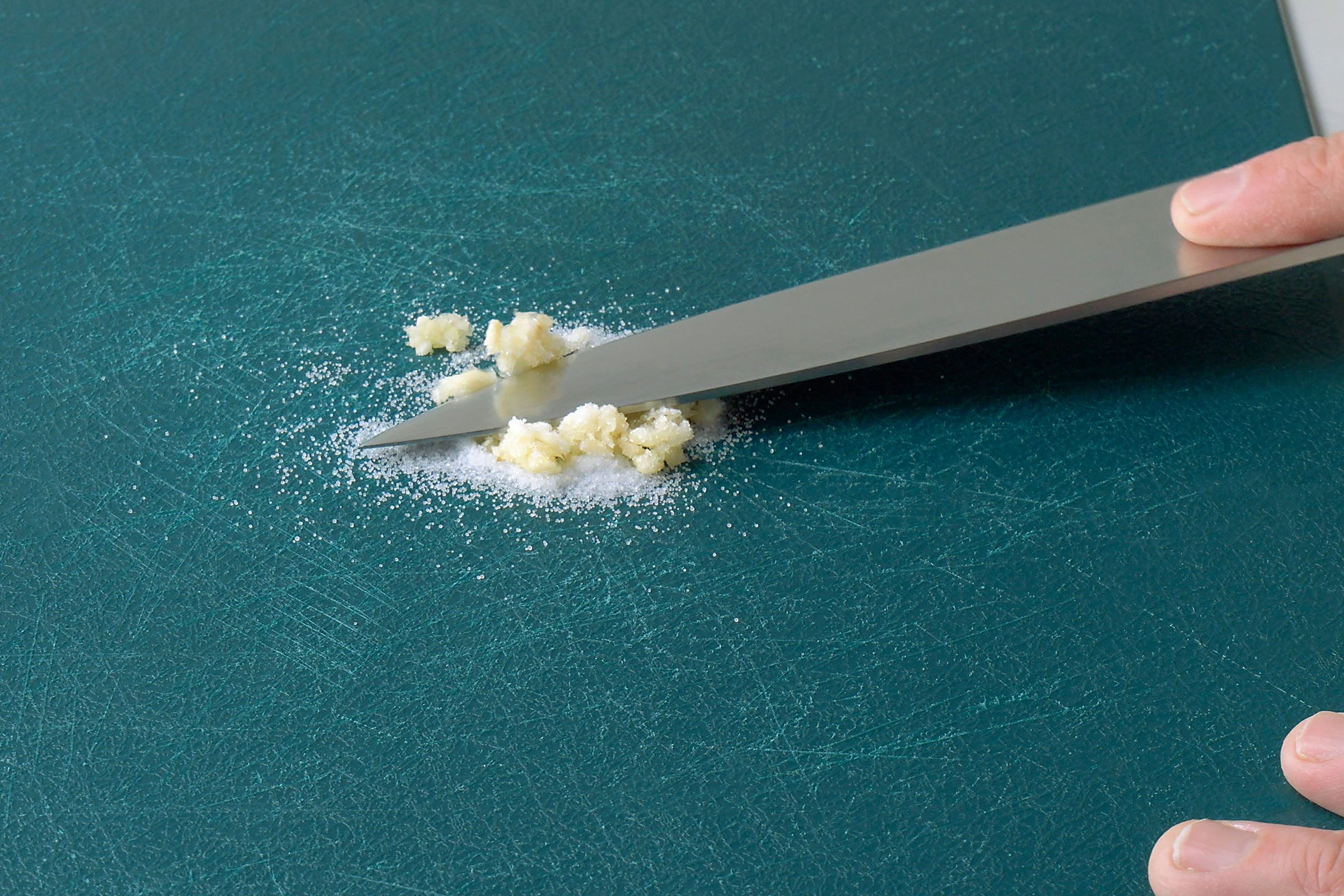 Crushing salt and grated garlic using a chef's knife