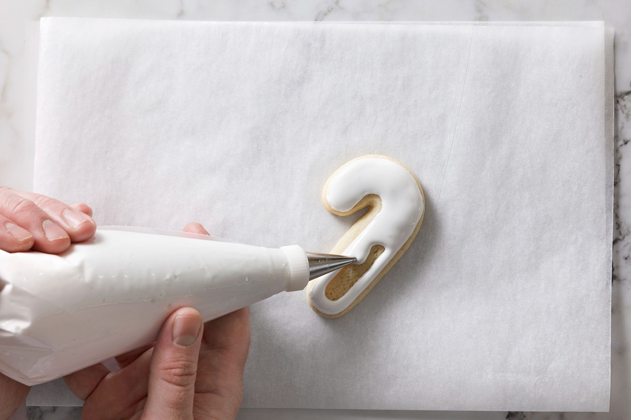 Christmas Cutout Cookies decorated with white frosting using a piping bag