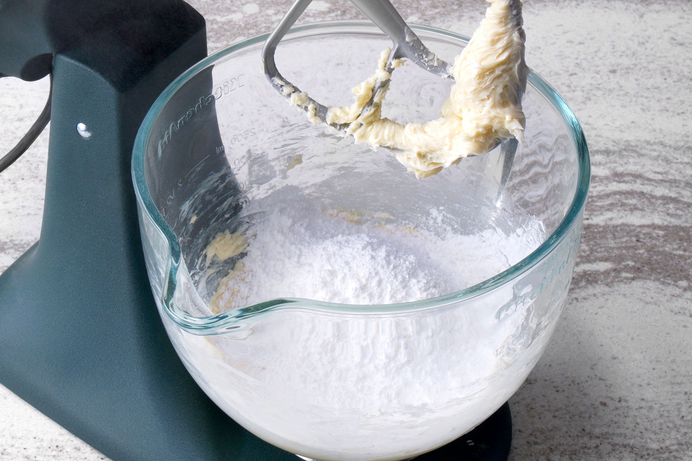 Creamed butter and sugar mixed together in a large glass bowl with a mixer