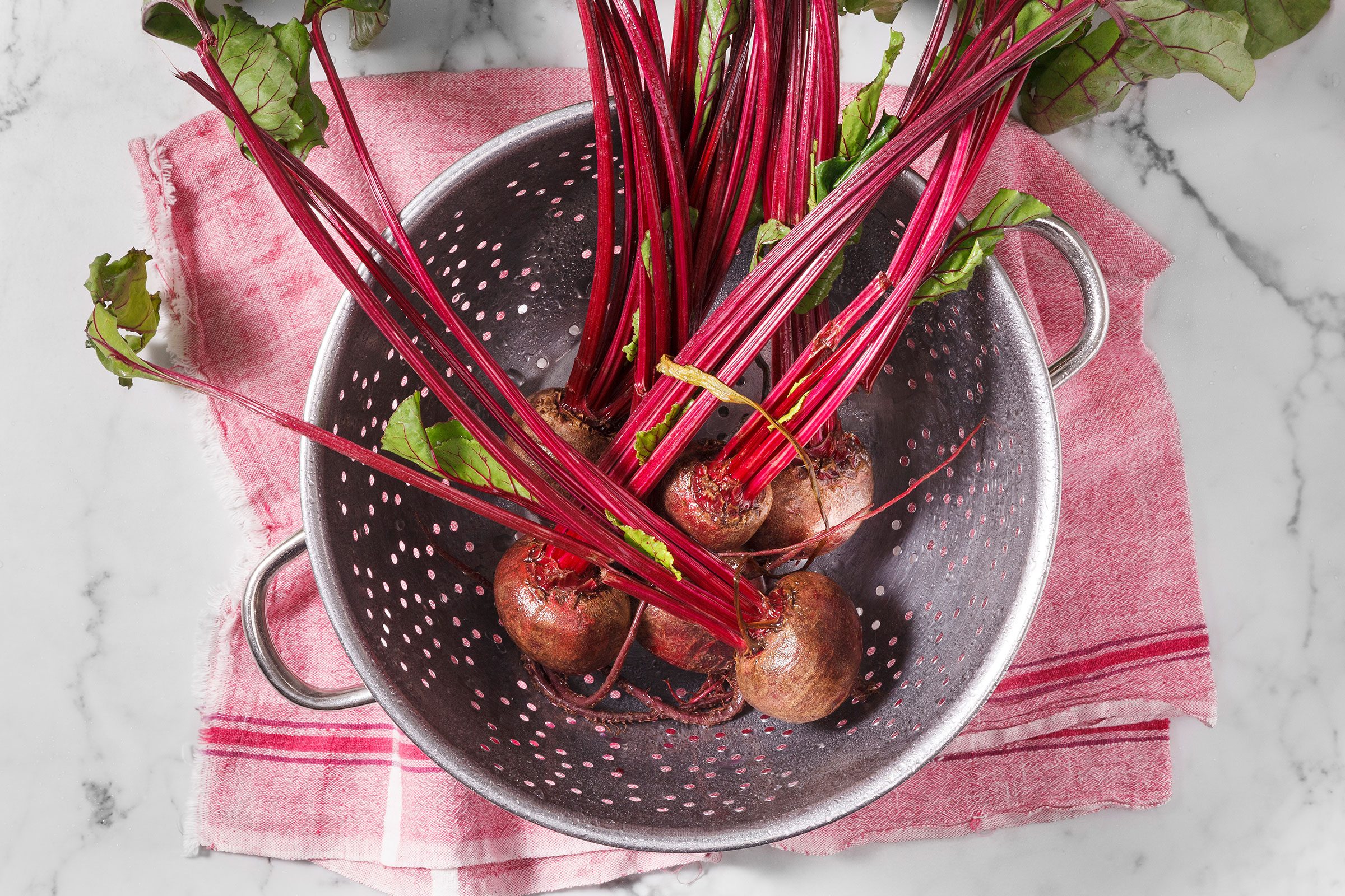 Beetroots inside a skillet with a red kitchen cloth beneath