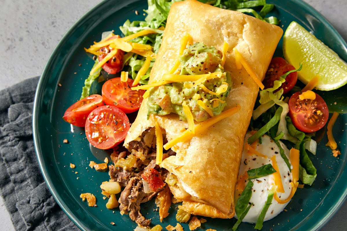 Close shot of Chimichangas; Serve on round plate with toppings of your choice; napkin; grey marble surface;