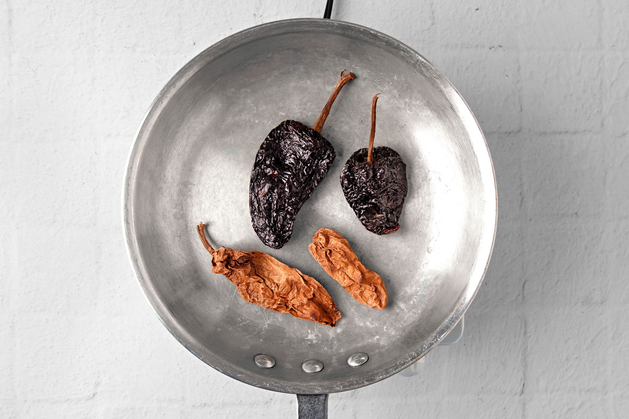 In a large dry skillet over medium-high heat, toast chiles on both sides until puffy