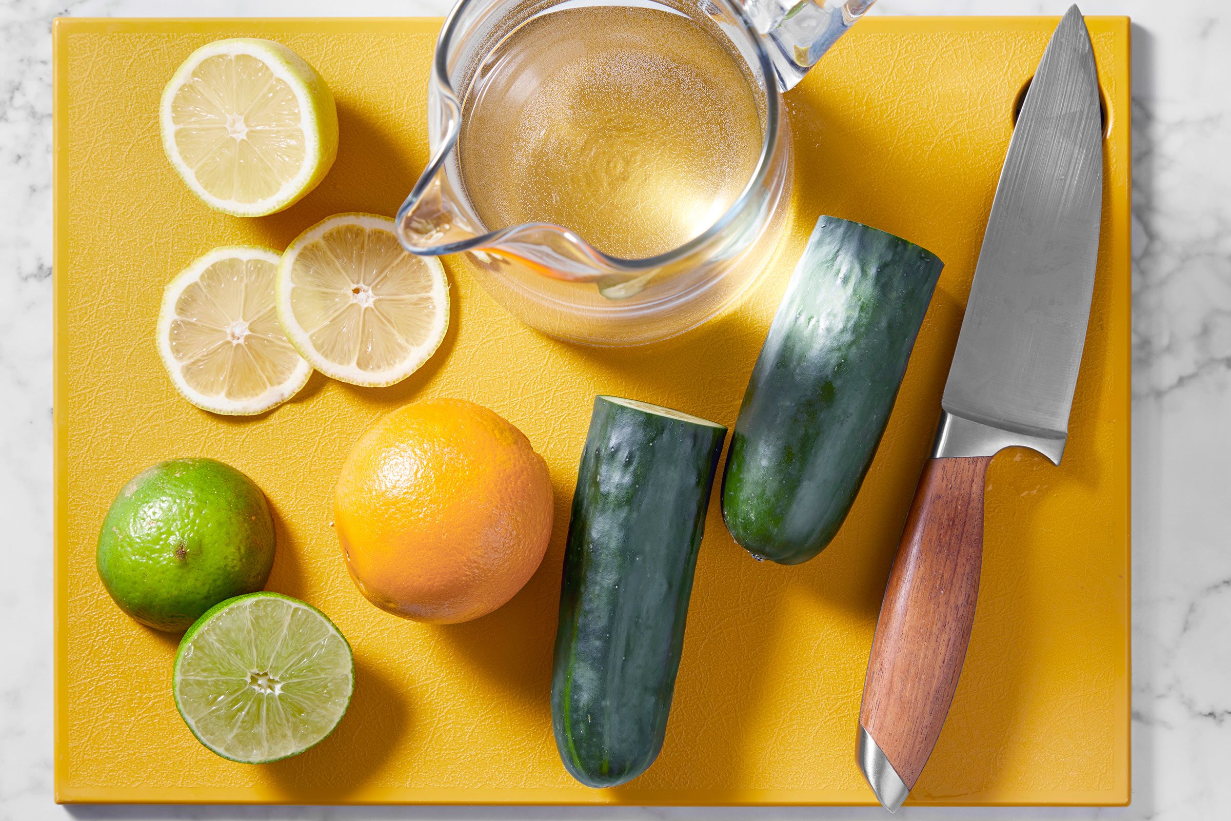 Ingredients to make Cucumber Water on a yellow surface