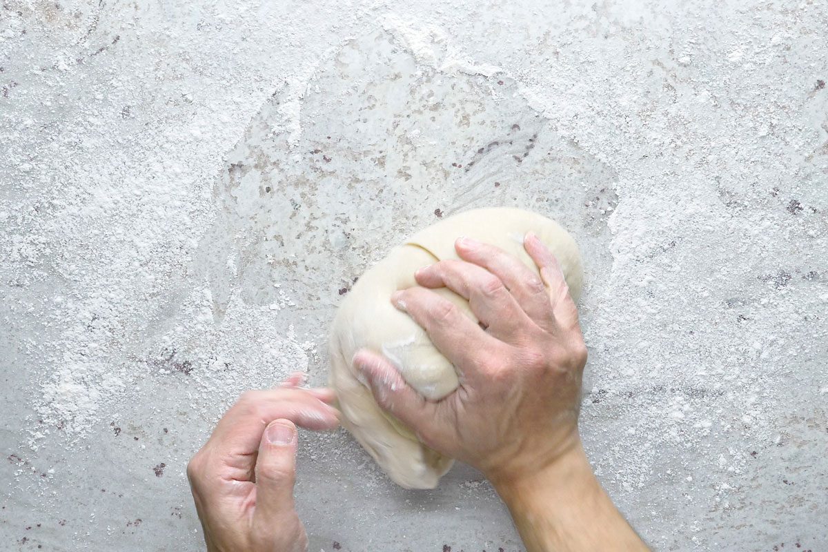 Overhead shot of turn dough onto a floured surface; knead until smooth and elastic 6-8 minutes; place in a greased bowl; turning once to grease the top; cover and let rise in a warm place until doubled; 1-1/2 to 2 hours; grey surface;