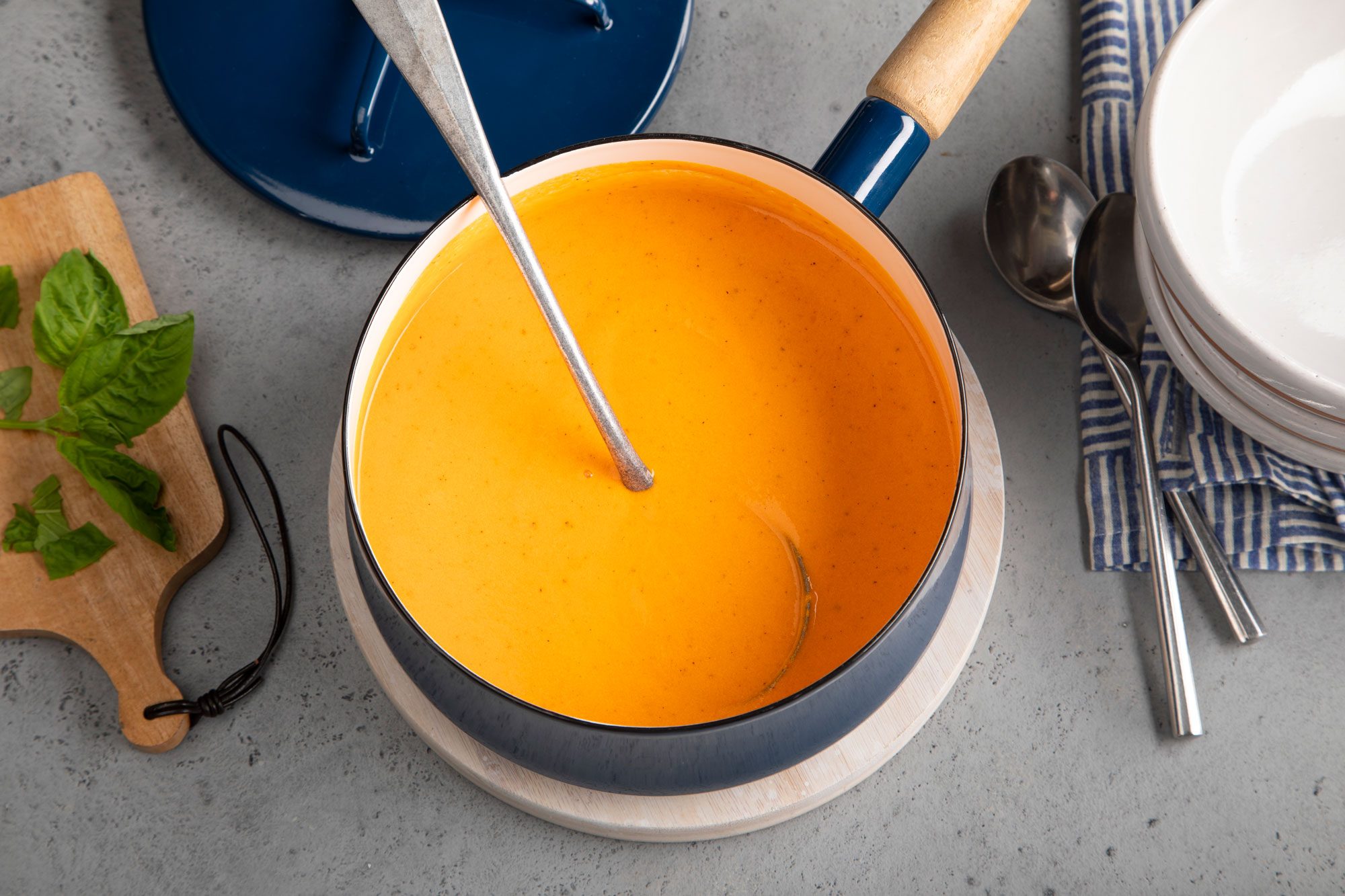 A steaming bowl of roasted red pepper soup with a spoon placed next to it, perfect for a cozy meal