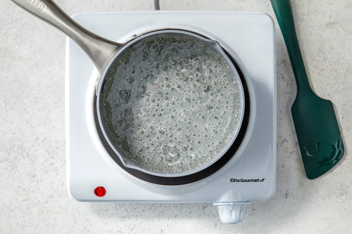 Overheda shot of reduce heat; simmer uncovered for 3-5 minutes or until sugar is dissolved; stirring occasionally; spatula; induction stove; marble surface