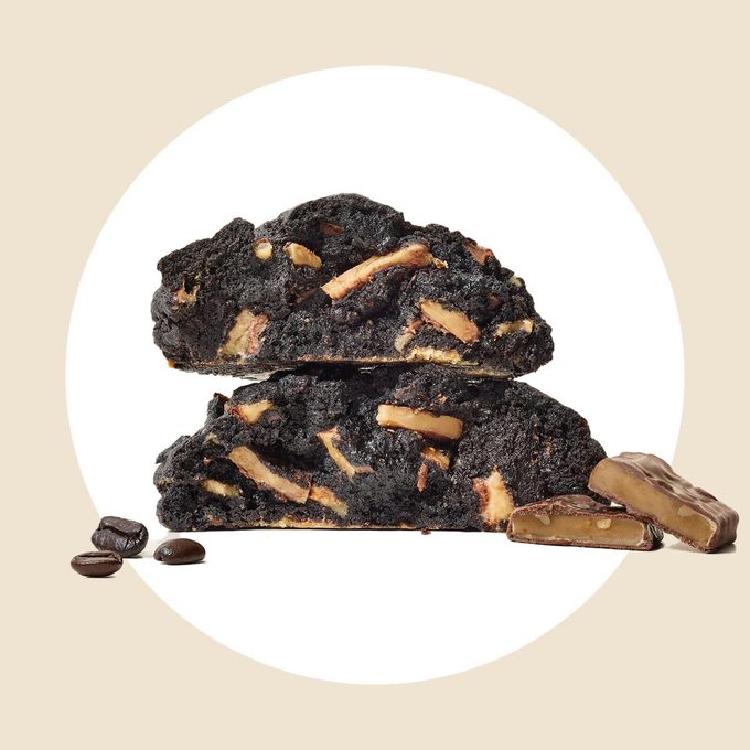 Two chocolate cookies cut in half and stacked, with toffee candy and coffee beans on a white and tan background