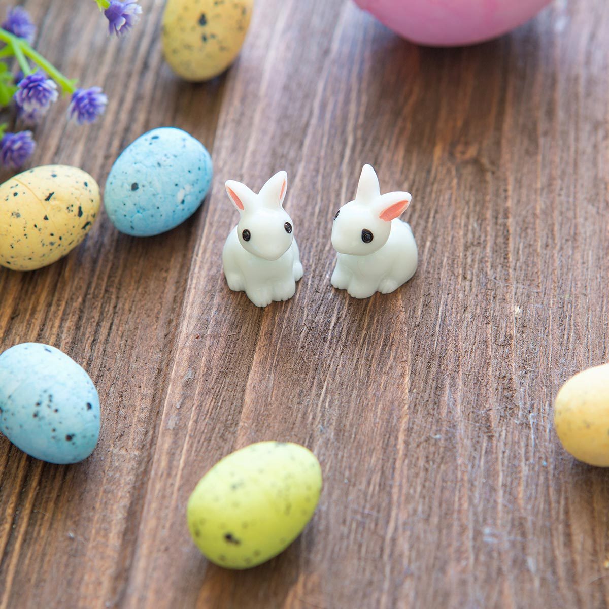 wo tiny Easter bunnies on the floor surrounded by Easter eggs.