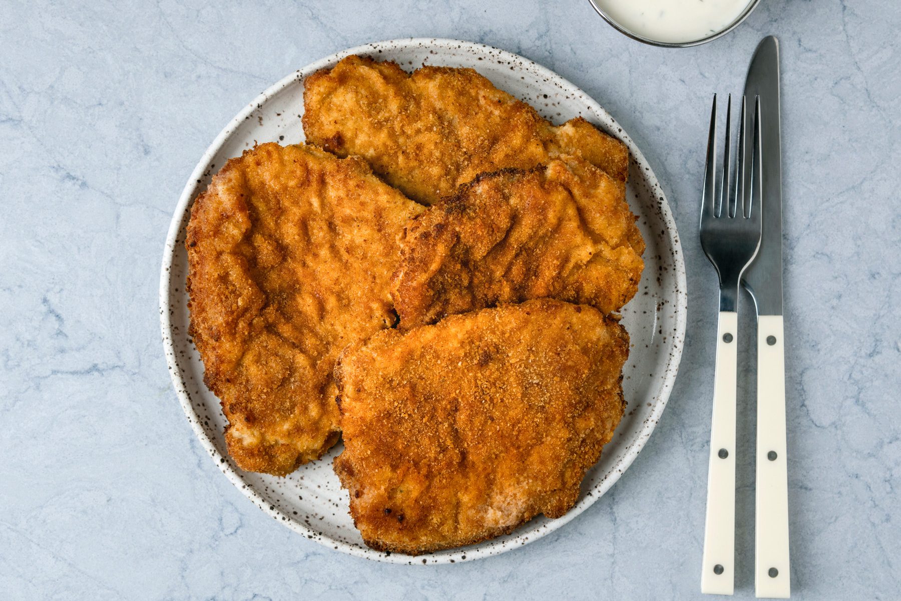 Air Fryer Pork Schnitzel is ready and served in a plate with sour cream.