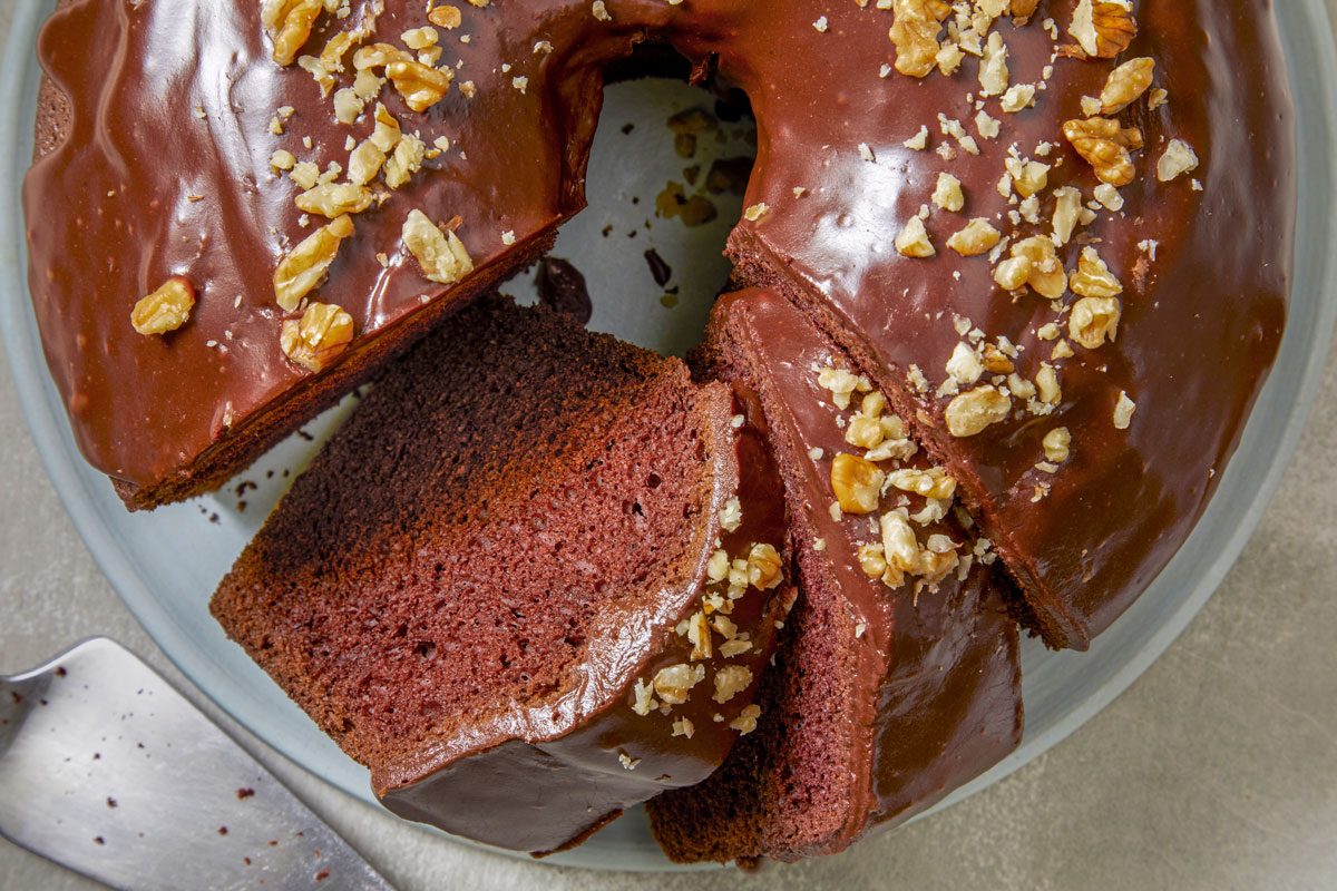 Close shot of Chocolate Chiffon Cake; placed on a plate; cut into slices; cake knife; marble surface;