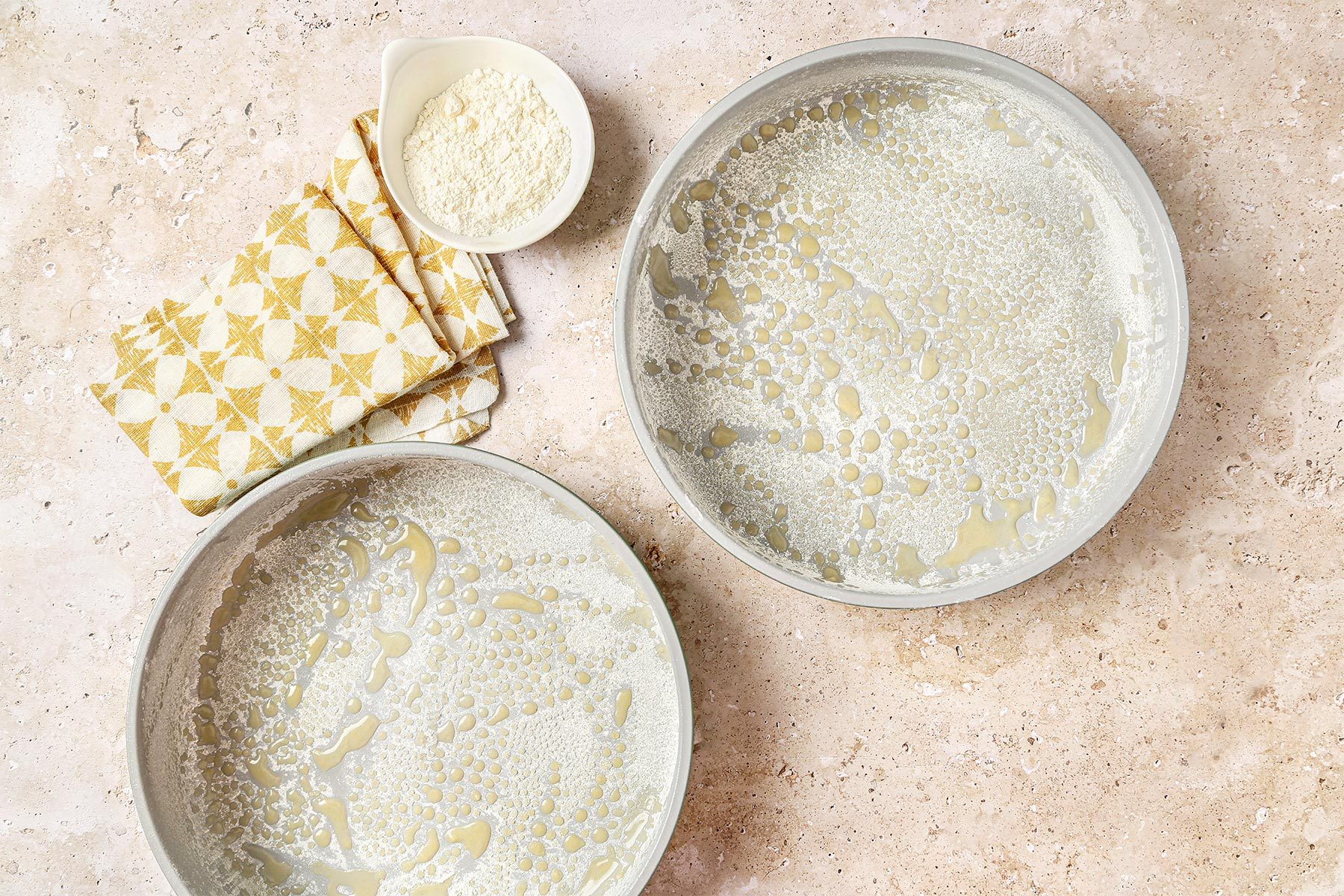 Cake pans buttered and floured with a yellow and white linen.
