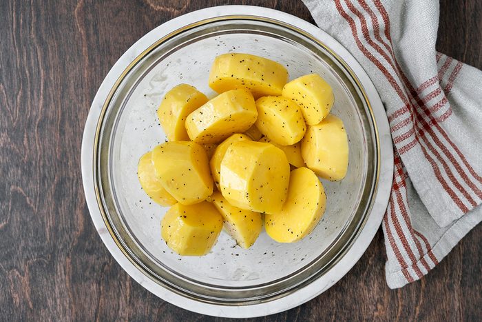 Large cut potatoes mixed in a bowl, seasoned with spices.