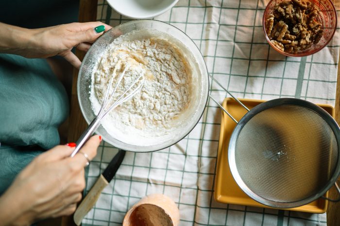 High angle view of woman holding whisk and bowl for baking