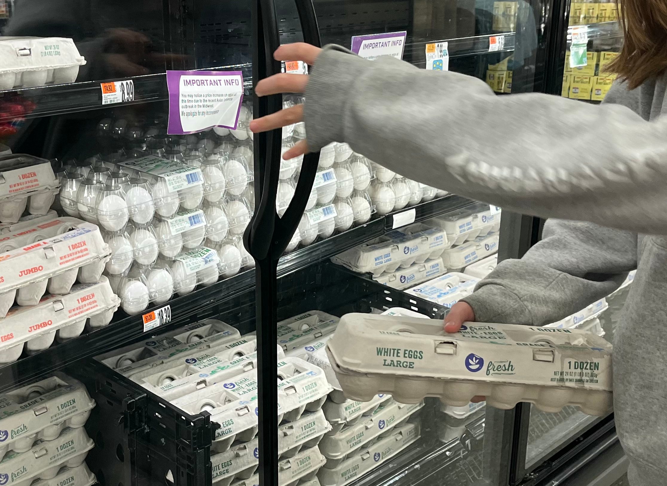 Customer holds a carton of eggs in front of a refrigerator at a Giant grocery store