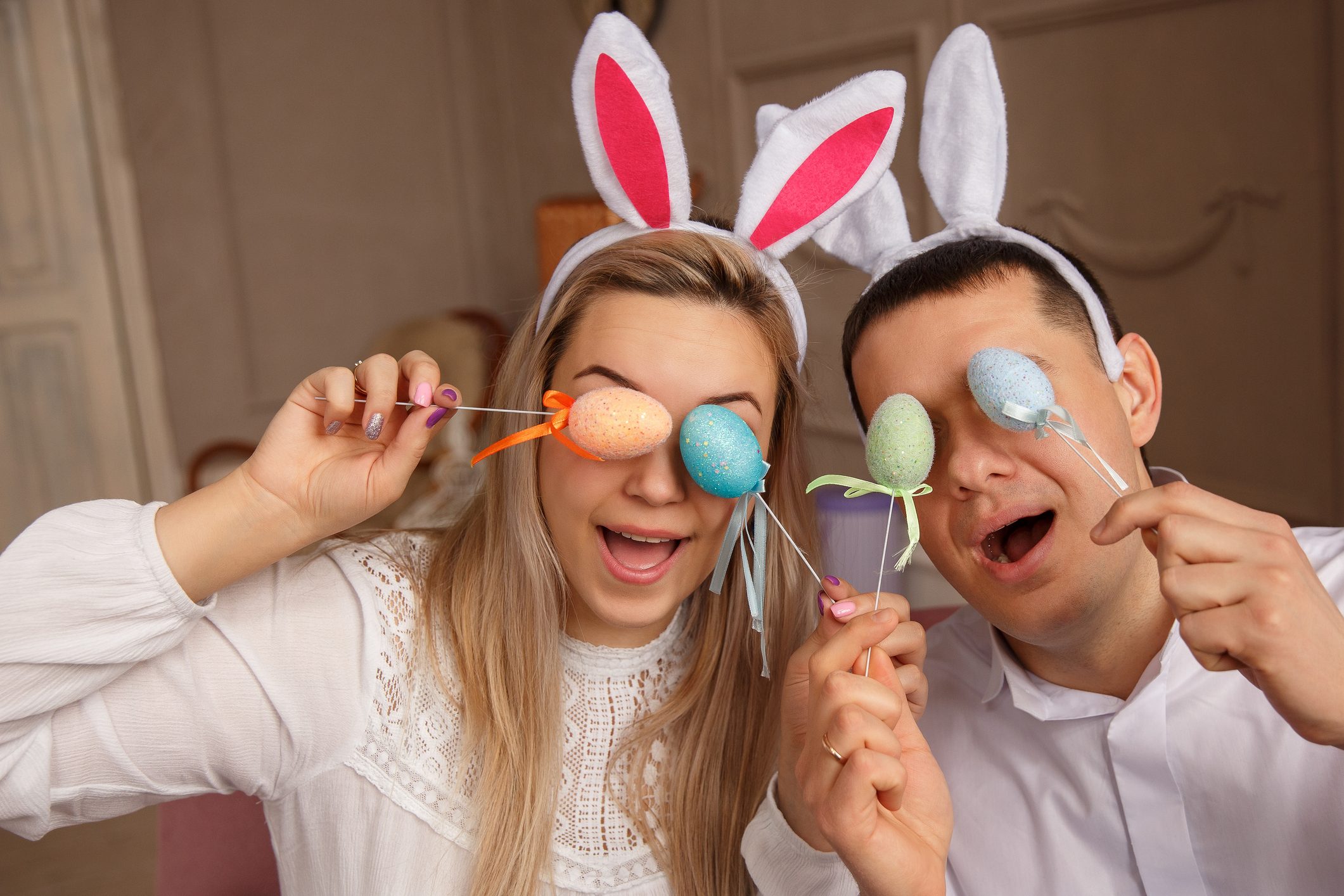 Happy Easter concept. Funny couple wearing bunny ears and having fun with Easter eggs at Easter day. Friends playing hunt eggs at Easter sunday