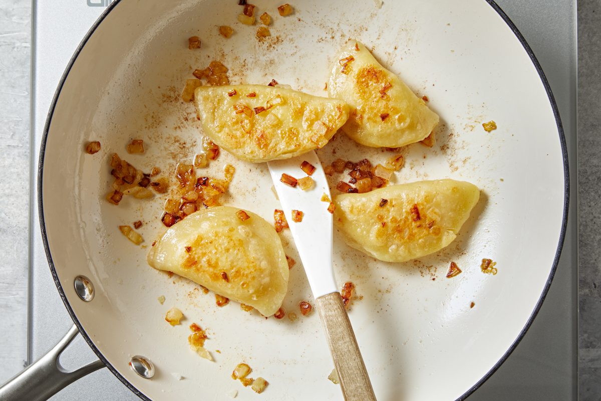 pierogis being fried in a pan
