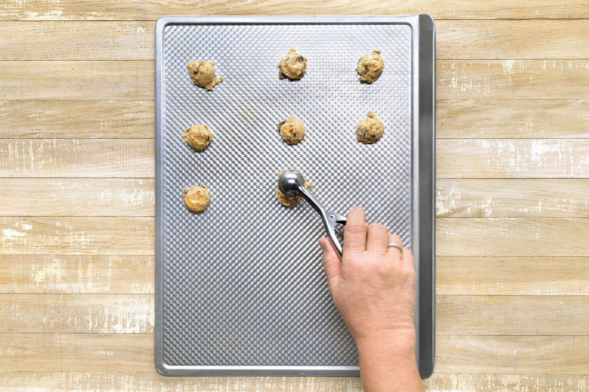 Overhead shot of shape into balls; Place 2 inch apart on ungreased baking sheets; wooden surface;
