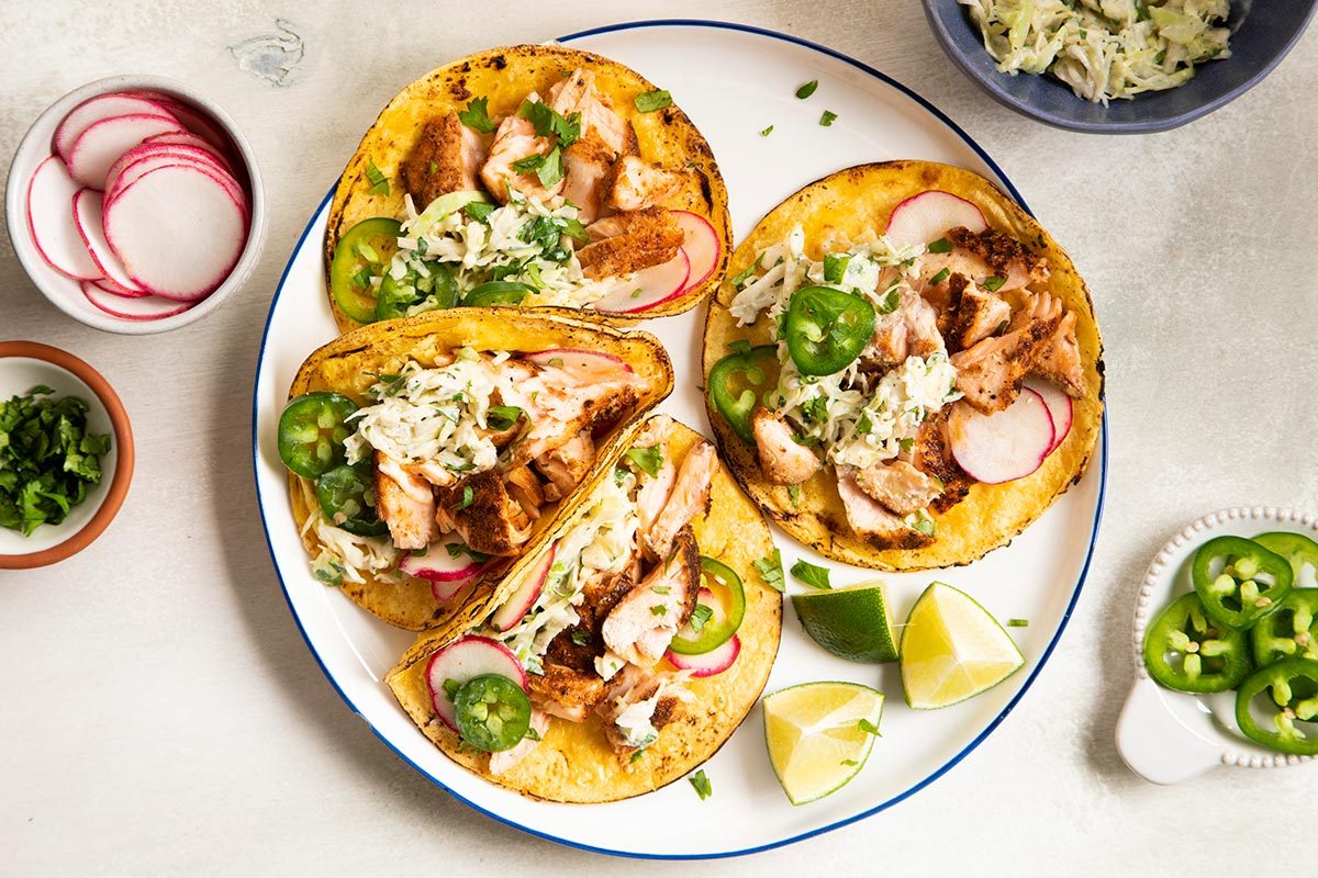Salmon taco served on a plate and lime wedges on the side.