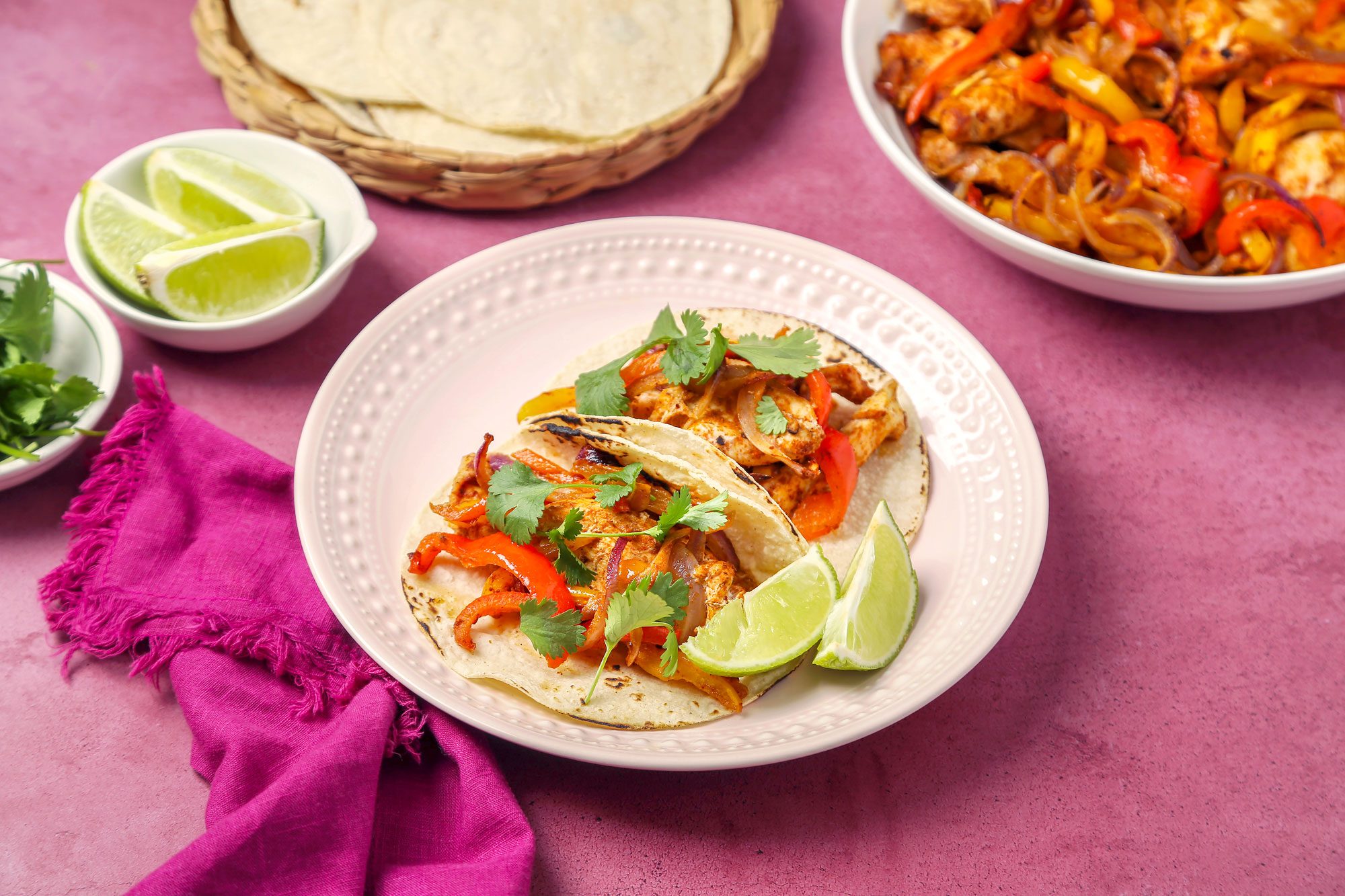 Fajitas served on tortillas on a pink plate.