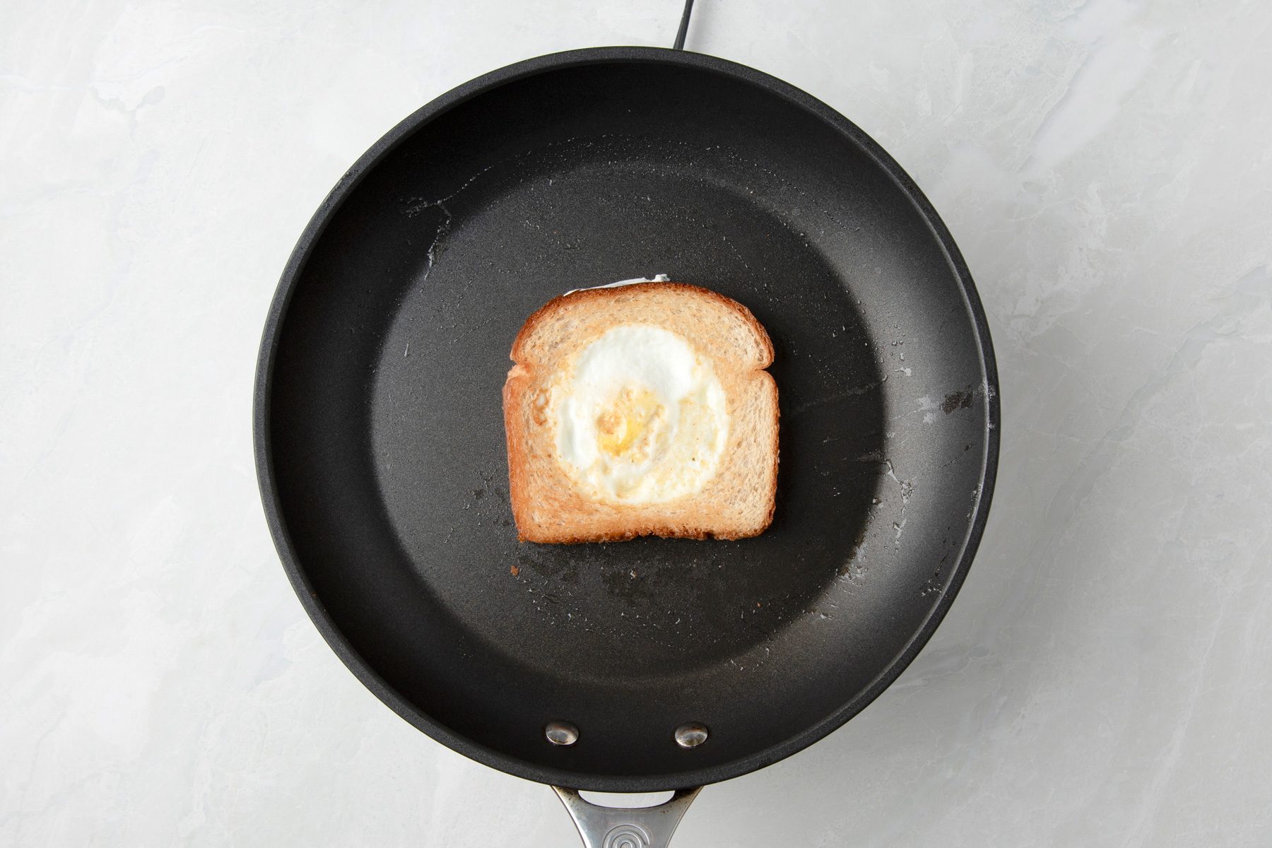 Overhead shot of turn and cook the other side until egg yolk is almost set; on marble surface;