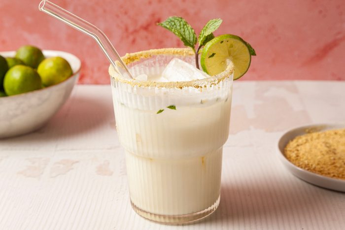 Key Lime Mojito in a glass with a glass straw and slice of lemon and few mint leaves