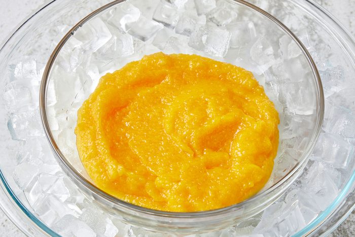 Mango puree into a glass bowl on top of an ice bath in a larger bowl