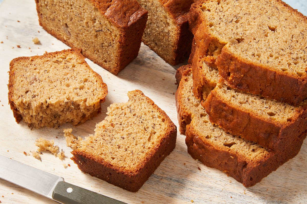 closeup shot of Peanut Butter Banana Bread, Slices of the bread are arranged on a wooden cutting board, A knife is positioned beside the bread
