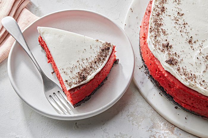 Overhead shot of Red Velvet Cheesecake; placed on a marble tray; cut into slice and served