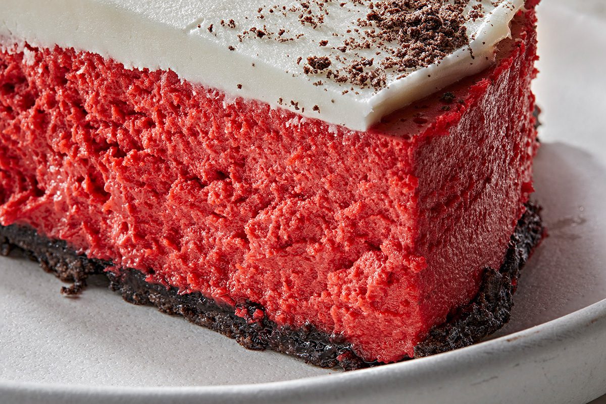 Close up shot of Red Velvet Cheesecake; cut into slice and served on white plate