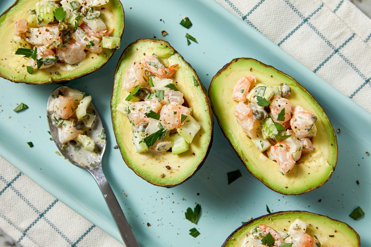 Close up shot of Shrimp Salad-Stuffed Avocados; garnish with additional parsley and serve immediately; spoon; napkin; all set on marble surface;