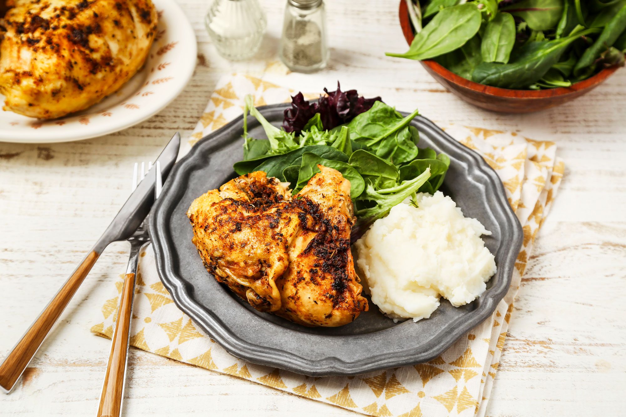 Cover push pull image of Taste of Home's Slow-Cooker Bone-In Chicken Breast shot on a white wooden surface; Bone-in chicken breasts cookedi n a slow-cooker and served on a metal plate with mashed potatoes and greens