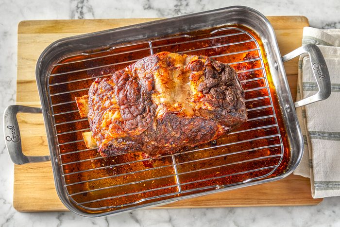 Overhead shot of add beef stock to drippings; bring to a boil; placed on wooden board with napkib; all set on a marble surface;