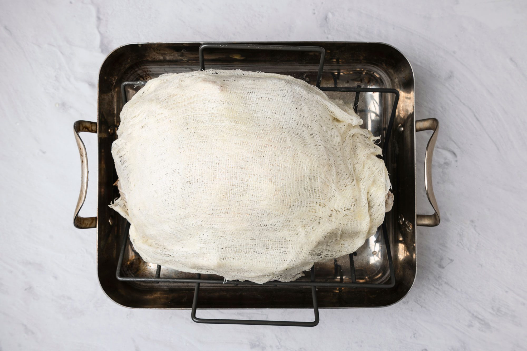 Overhead shot; In a large saucepan melt cubed butter; stir in wine; Saturate a four-layered 17-inch square of cheesecloth in butter mixture; drape over turkey; Bake turkey; uncovered 3 hours; baste with wine mixture every 30 minutes; keeping cheesecloth moist at all times; marble surface;