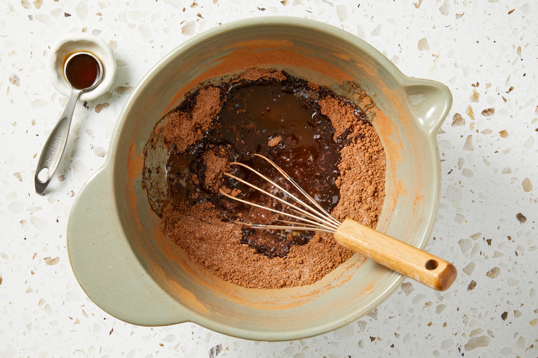 Overhead shot of a large bowl combine sugars and baking cocoa; Whisk until free of clumps; whisk in melted butter and vanilla extract; Preheat oven to 350 degree; Line an 8x8-inch baking pan with parchment paper; coat with cooking spray; marble surface;