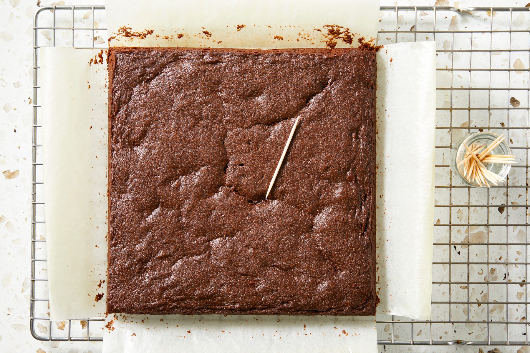 Overhead shot; Use edges of the parchment paper to lift brownies from the pan; Allow brownies to cool on a wire rack at least one hour before cutting; marble surface;