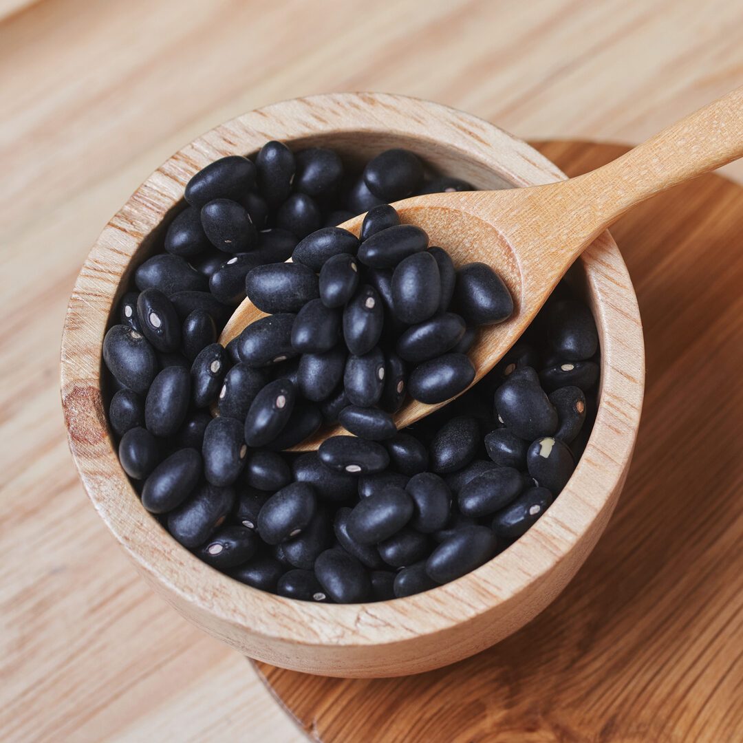 The black beans and wooden spoon in a wooden cup
