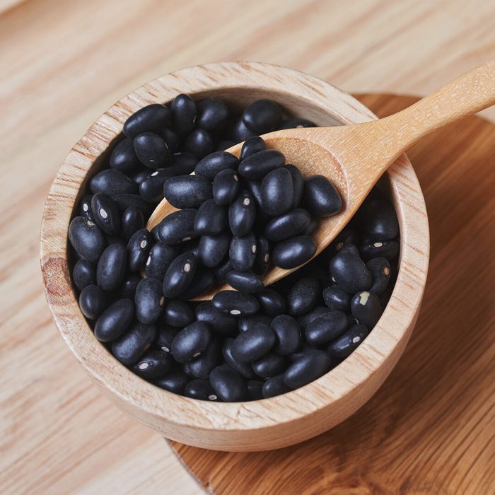 The black beans and wooden spoon in a wooden cup