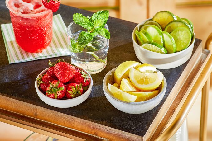 Drinks, Lime wedges and strawberries are on table for outdoor drink station set up