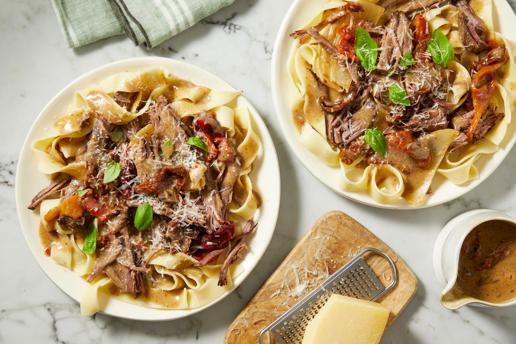 Overhead shot of Marry Me Pot Roast served on plates on a marble countertop,