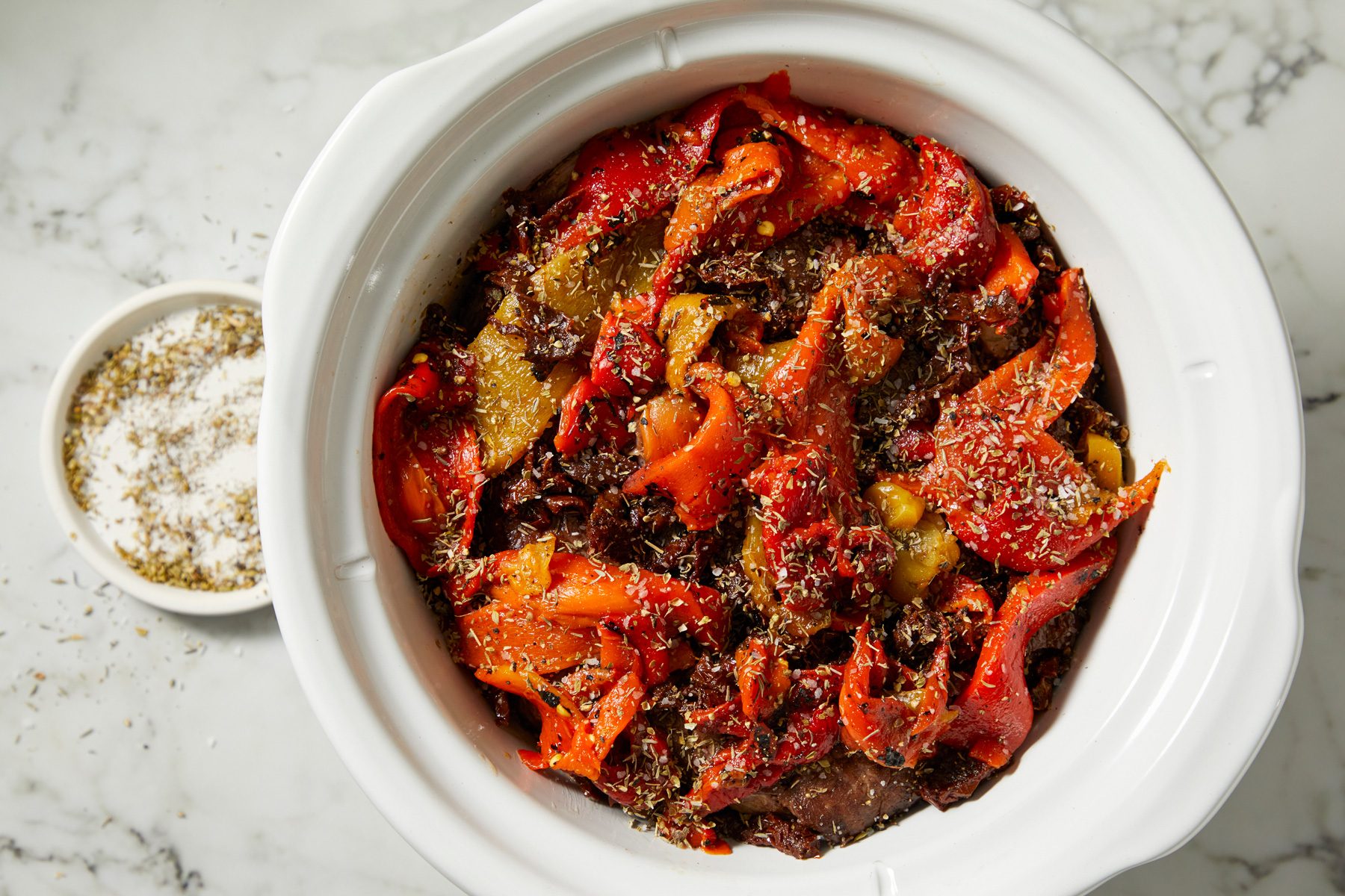 Sliced sun-dried tomatoes and roasted red peppers scattered around roast, seasoned with oregano, thyme, salt, and pepper, topped with cream of mushroom soup.