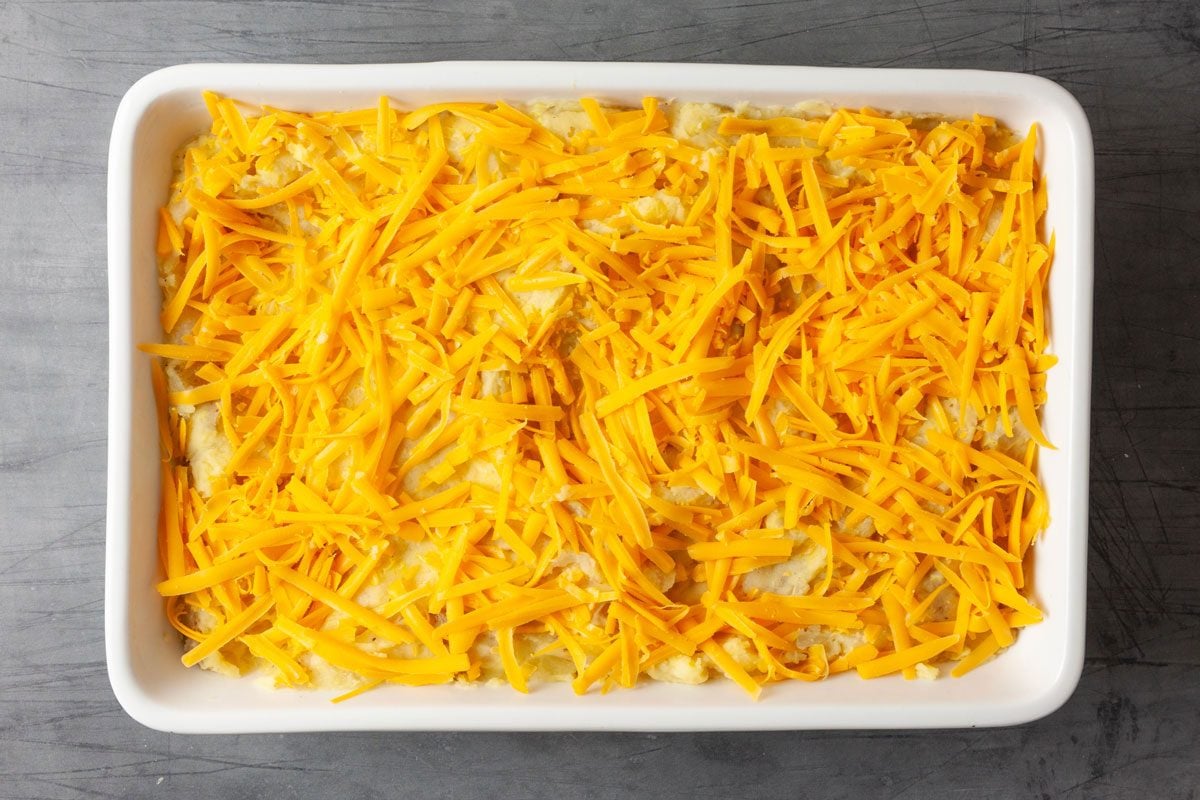 Scoop the mash into a lightly greased 13x9-inch pan and and sprinkle with the grated sharp cheddar cheese